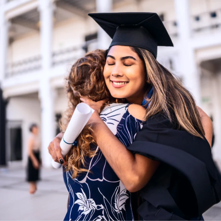 Persona celebrando un logro académico al recibir su diploma, acompañada por un familiar en una ceremonia de graduación.