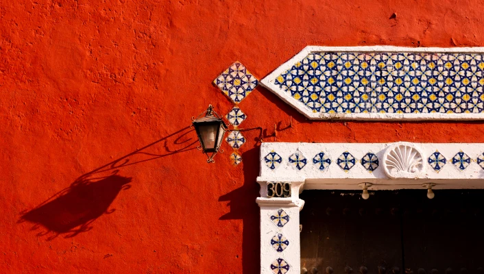 Fachada color terracota con detalles de mosaico artesanal y farol decorativo, representando arquitectura tradicional mexicana.