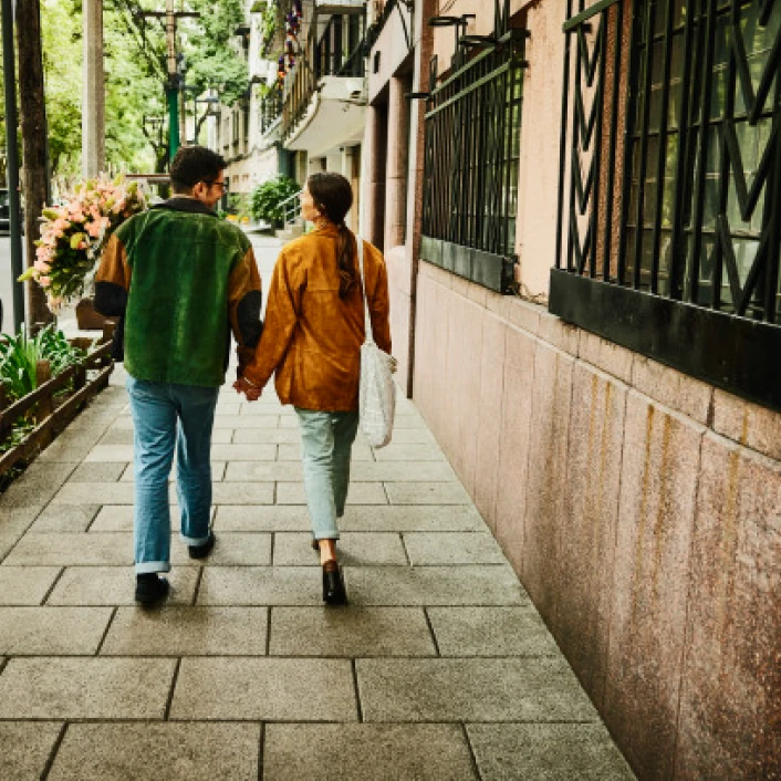 Pareja caminando por una calle residencial arbolada, reflejando estabilidad, bienestar y proyectos compartidos a largo plazo.