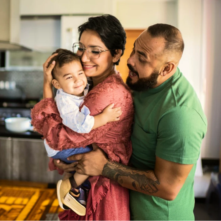 Familia abrazando a un menor dentro del hogar, reflejando protección, bienestar familiar y tranquilidad en un entorno residencial.
