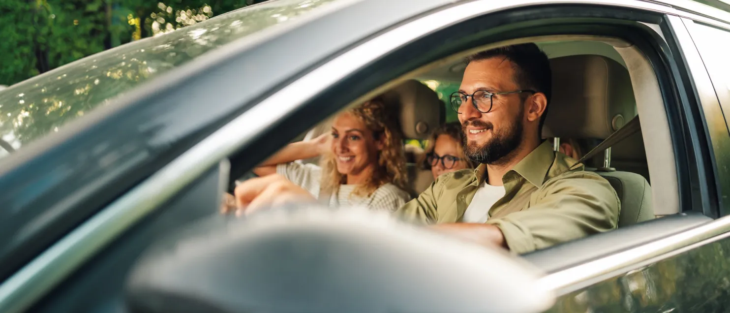 Familia disfrutando un viaje por carretera, con personas adultas y menores a bordo de un automóvil durante un trayecto recreativo.