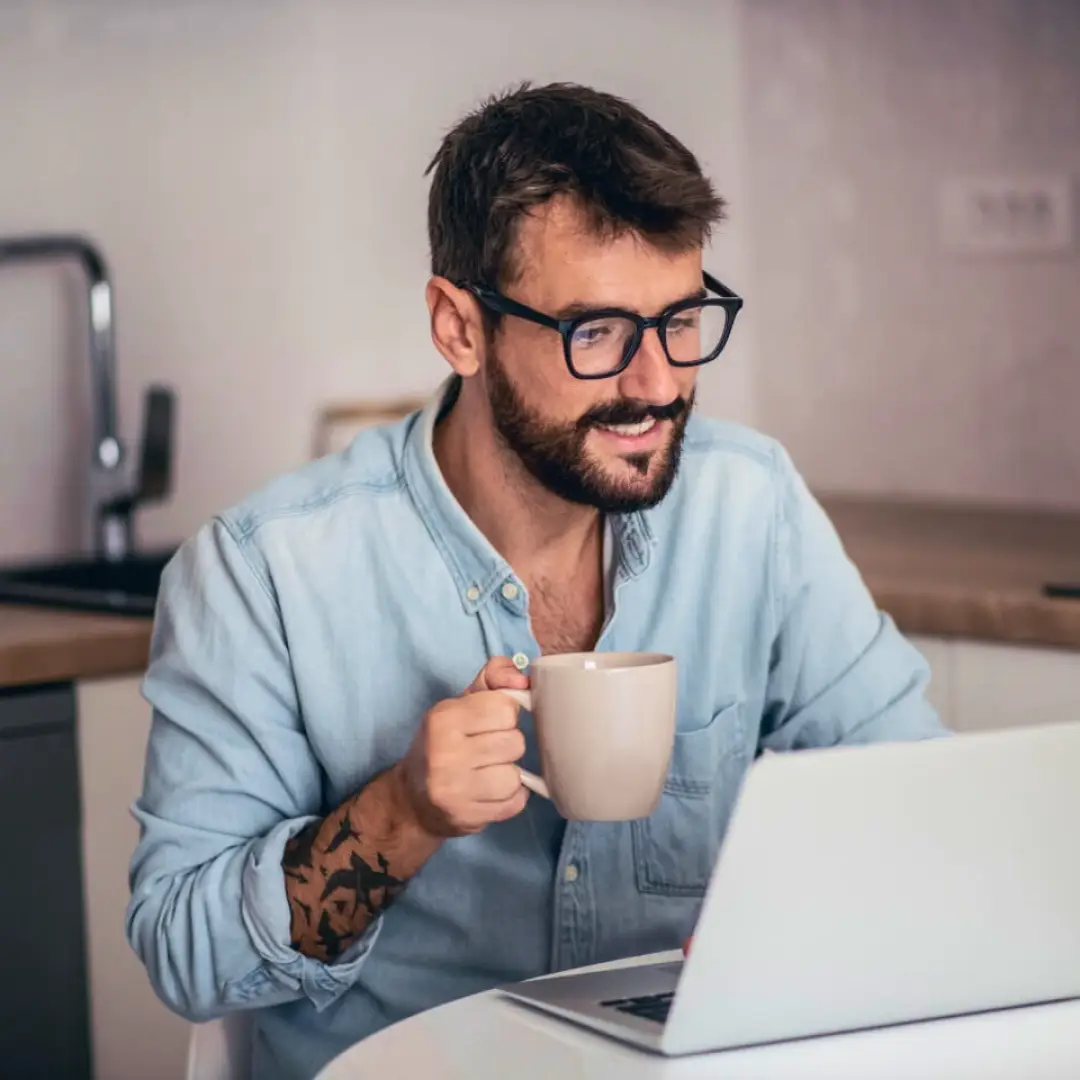 Persona utilizando una computadora portátil desde casa mientras consulta información y realiza gestiones digitales en un entorno cómodo y conectado.