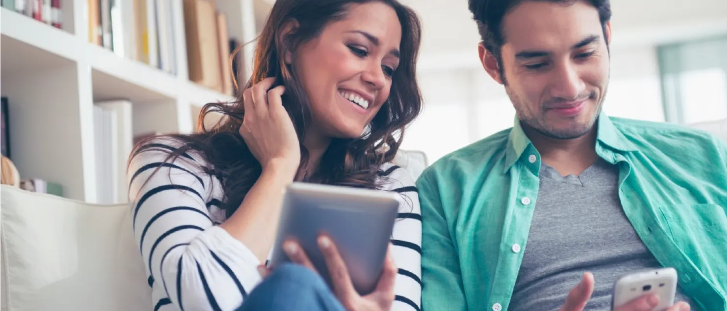 Pareja consultando información financiera desde una tablet y un teléfono móvil para planificar metas, ahorro e inversiones a futuro.