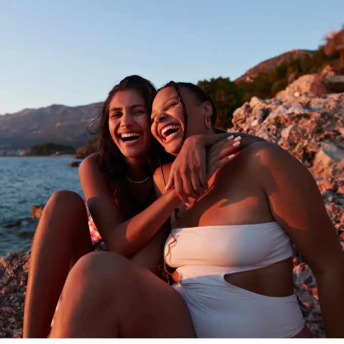 Dos personas disfrutando un viaje junto al mar al atardecer, compartiendo un momento de convivencia, descanso y experiencias memorables.