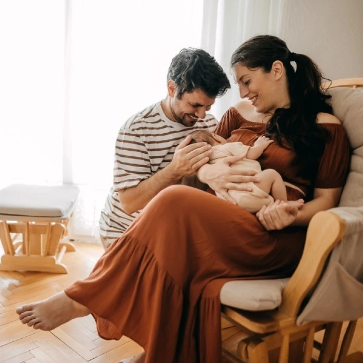 Familia con un bebé compartiendo un momento de cuidado y unión en el hogar, reflejando bienestar, protección y tranquilidad familiar.