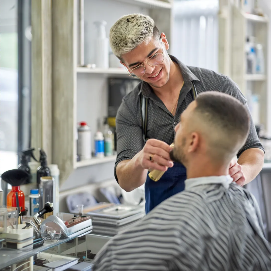 Persona propietaria de una pyme atendiendo a un cliente en una barbería, respaldando la continuidad y protección de su negocio.