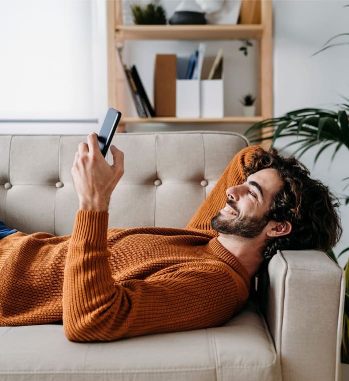 Joven descansando con celular en mano.