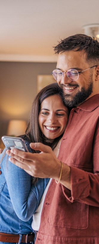 Una pareja abrazada mientras revisan su celular.