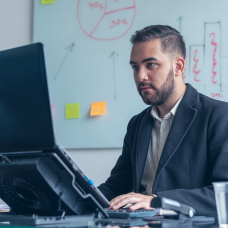 Un hombre sentado frente a su laptop trabajando en su oficina