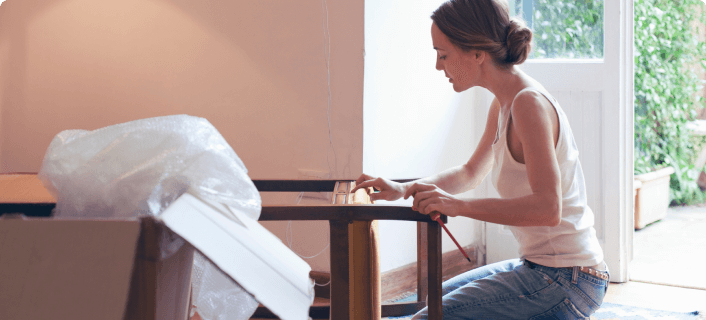 Una mujer sosteniendo un desarmador mientras repara una silla.
