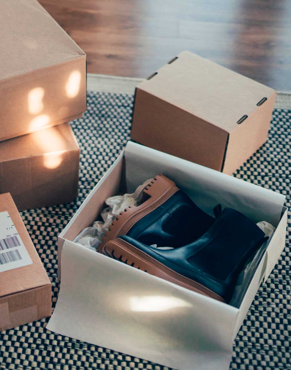 Varias cajas de compras en el piso, con una caja abierta mostrando un par de botas.