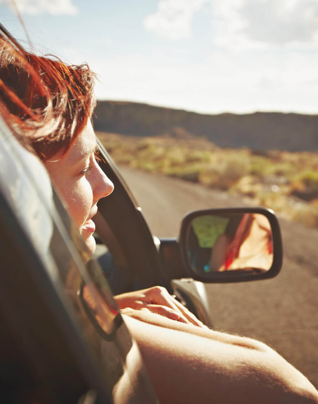 Mujer viendo por la ventana en un carro durante un viaje por carretera.