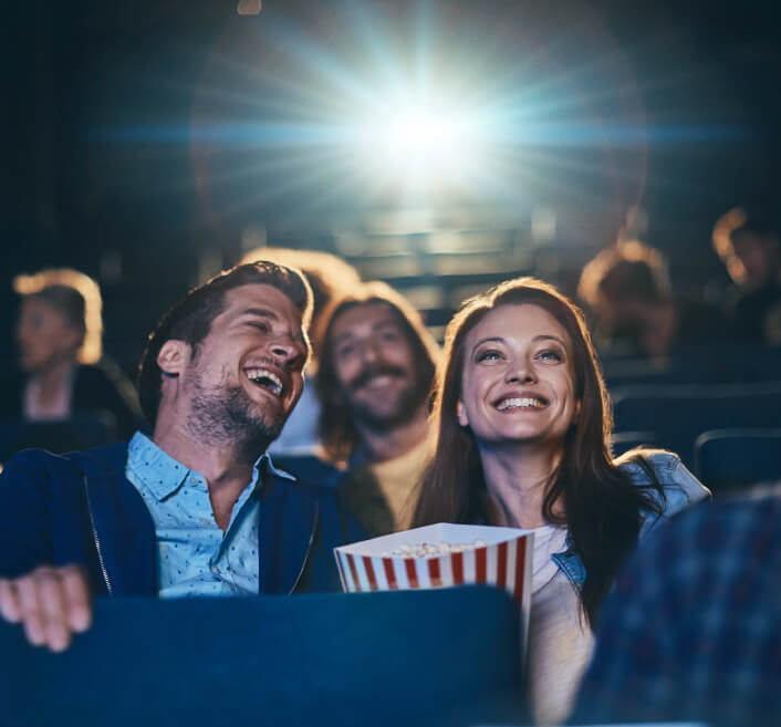 Pareja disfrutando de una experiencia agradable en el cine, con una caja de palomitas.