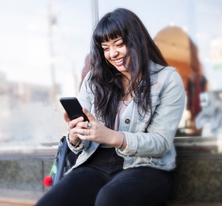 Joven cargando una mochila sobre sus hombros, ingresando su tarjeta de débito en un cajero.
