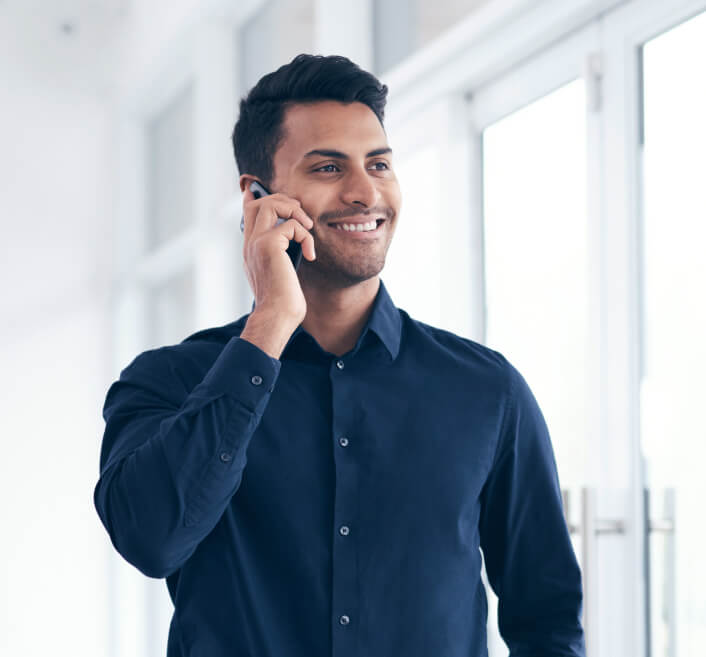 Hombre joven sonriendo mientras habla por celular.
