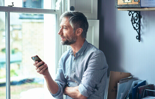 Hombre sosteniendo un celular en sus manos.