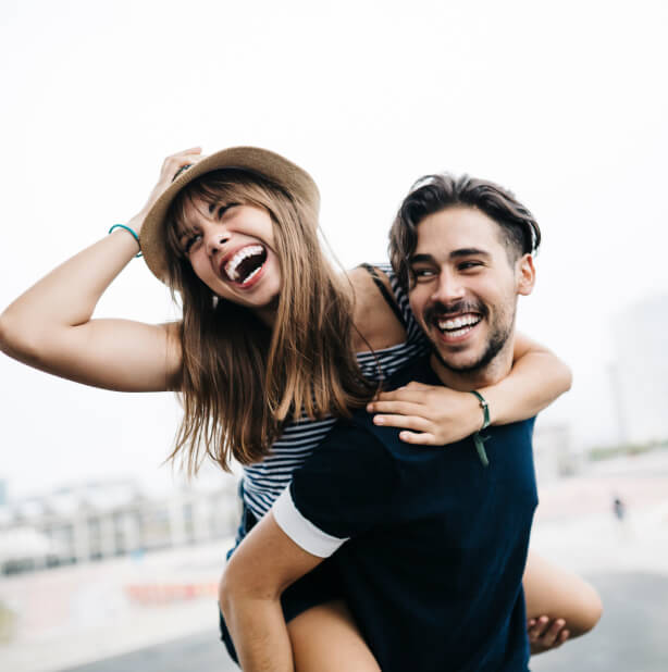 Joven sonriente sobre la espalda de un joven.