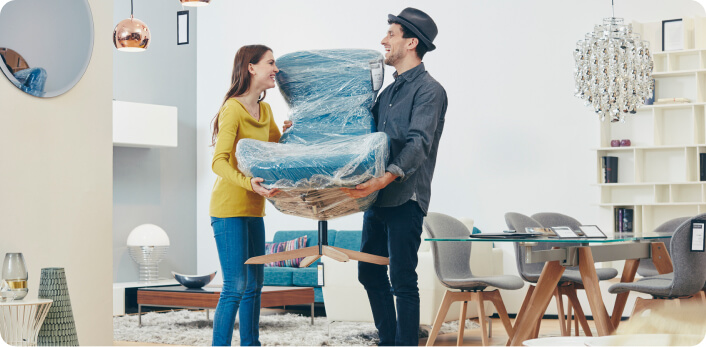 Una pareja cargando una silla nueva para su casa.