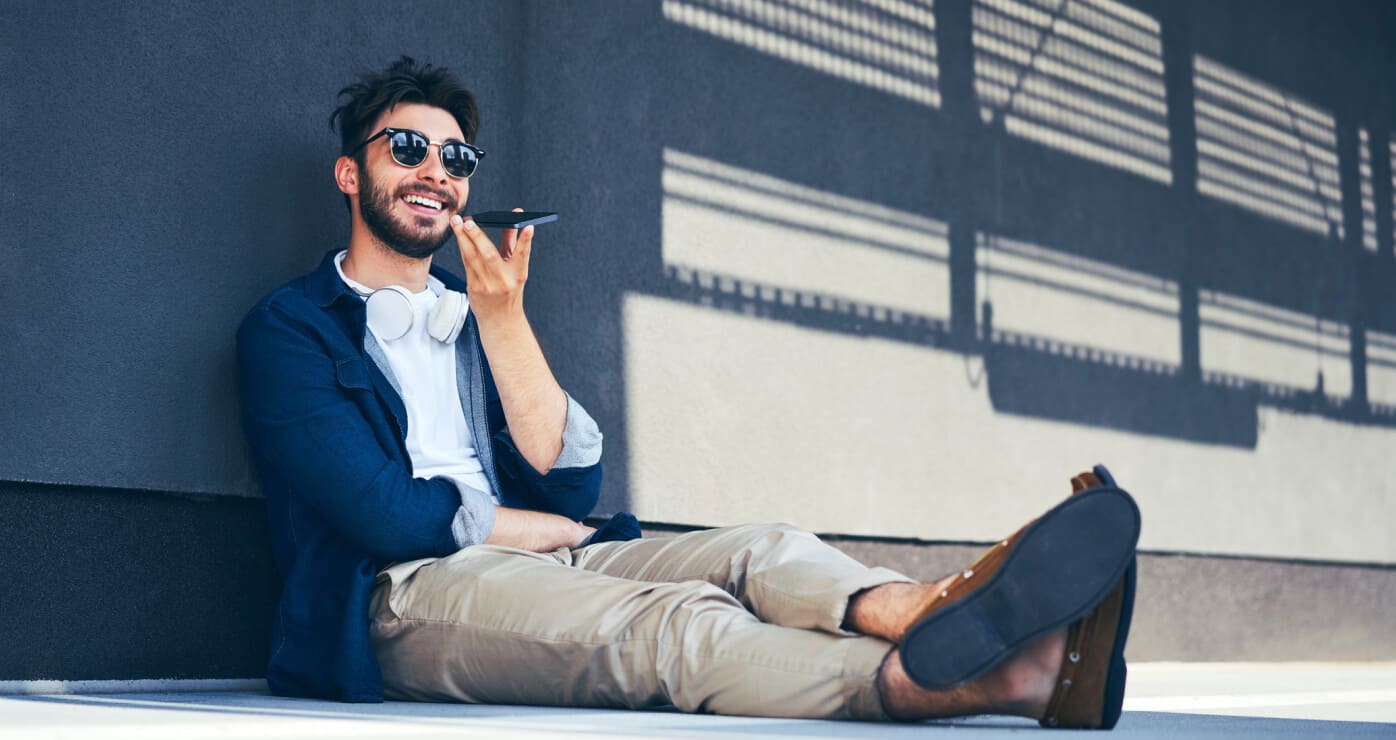 Joven sentado sonriendo y hablando por teléfono.