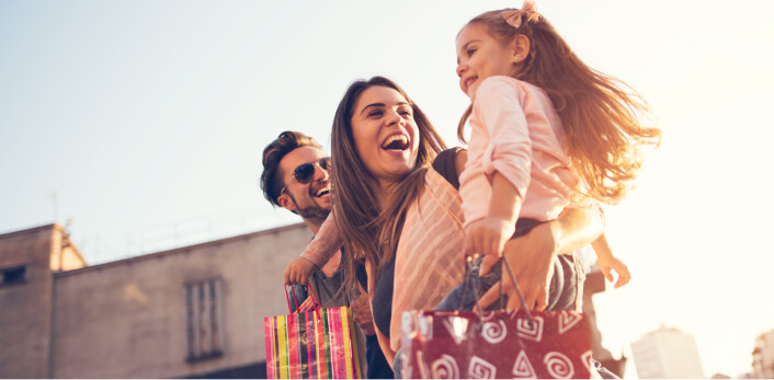 Una familia sonríendo mientras sostenien bolsas de compras.