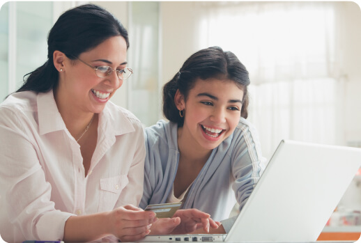 Una madre y su hija miran su laptop para comprar algo en línea.