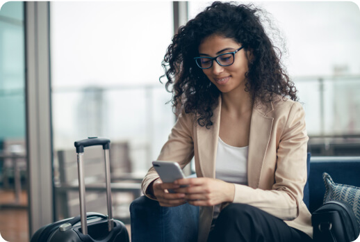 Una joven espera su vuelo mientras ve su celular.