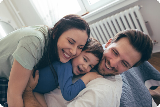 Unos padres abrazando a su hijo mientras sonríen.