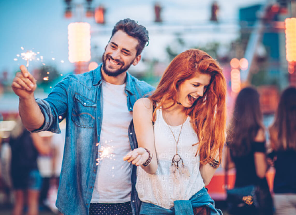 Una pareja sosteniendo luces de bengala mientras disfruta un concierto al aire libre.