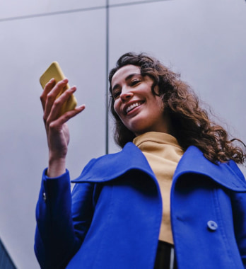 Una mujer feliz sosteniendo su celular.