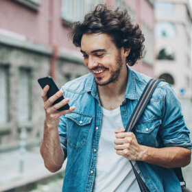 Joven caminando por la calle mientras revisa su nómina en su app móvil.