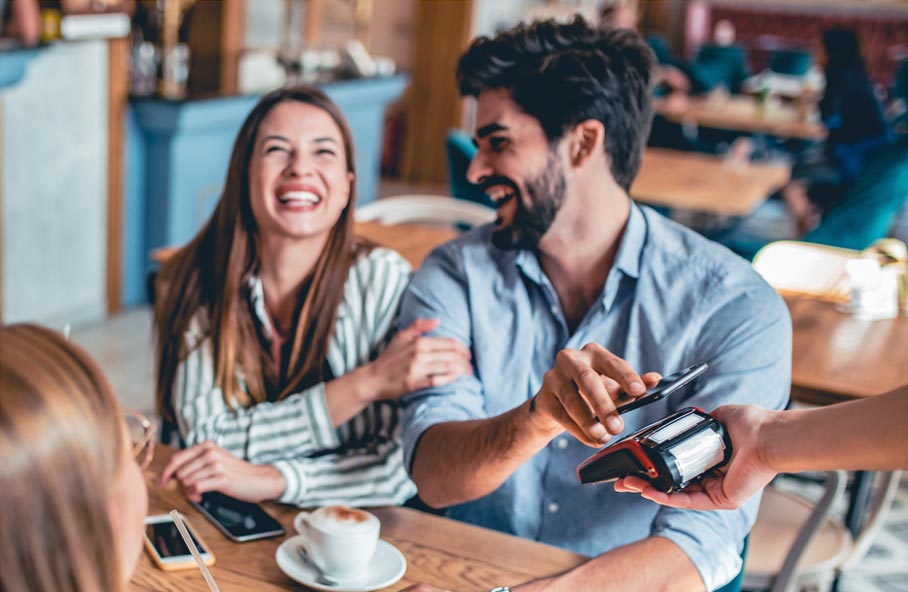 Una pareja disfrutando de un momento agradable en un restaurante y pagando con Apple Pay.