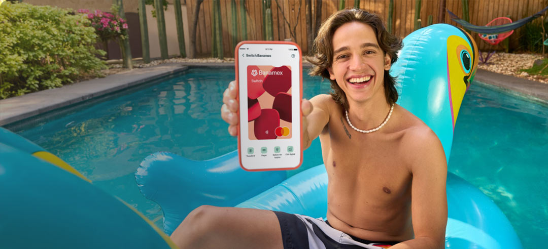 Joven sonriendo en un bosque, sosteniendo su celular mientras realiza una acción con su tarjeta MiCuenta.