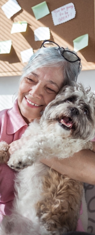 Una mujer de la tercera edad sonríe mientras abraza a un perro.
