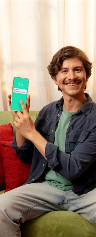 Un hombre sonriente mostrando su celular con una notificación de su nómina Banamex en la pantalla.