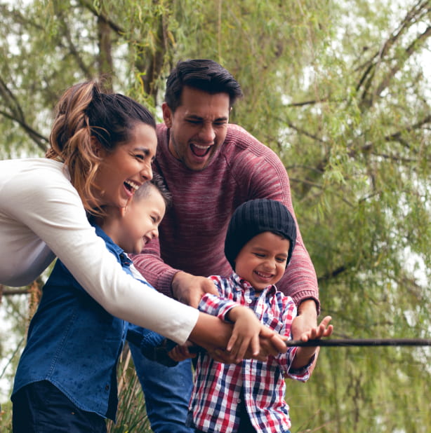 Pareja sonriendo y jugando con sus dos hijos pequeños.