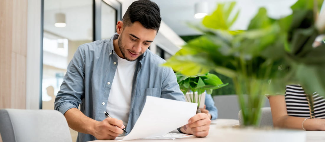 Un chavo con unos papeles en la mano revisando la información de su Afore.