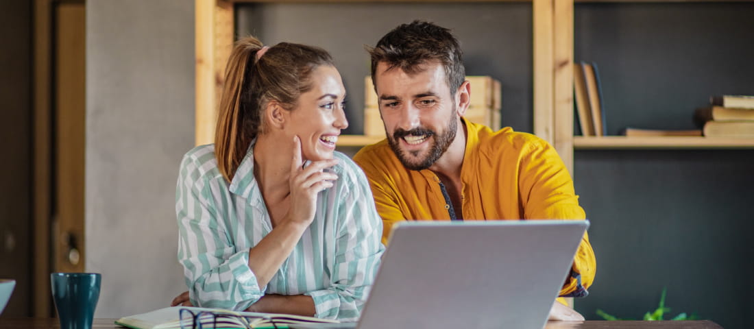 Una pareja revisando sus inversiones financieras en una laptop.