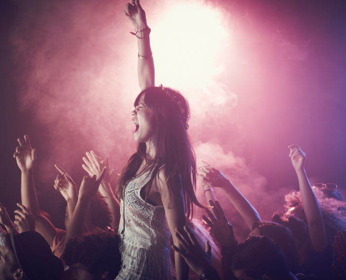 Una mujer con los brazos levantados disfrutando de un concierto.